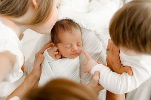 siblings kissing new baby