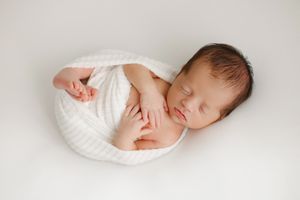 baby wrapped on white blanket