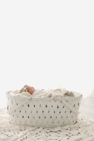 little baby in a white basket in a white studio