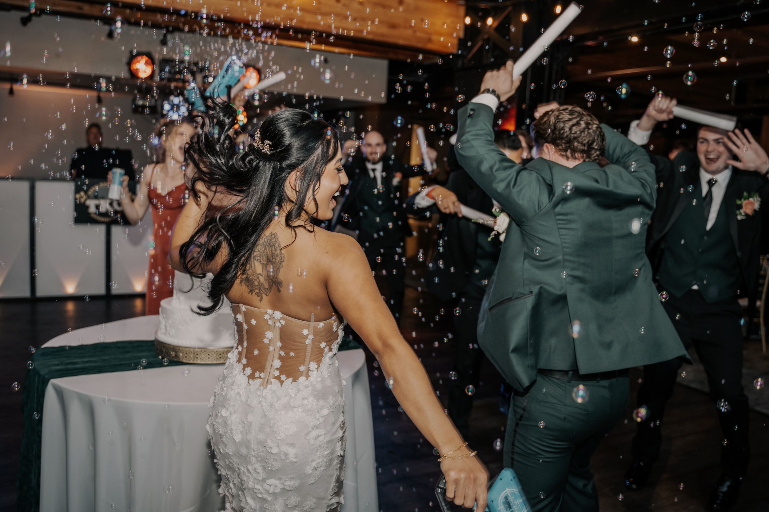 Wedding reception guests dancing and celebrating while confetti falls at an indoor venue during a lively party.