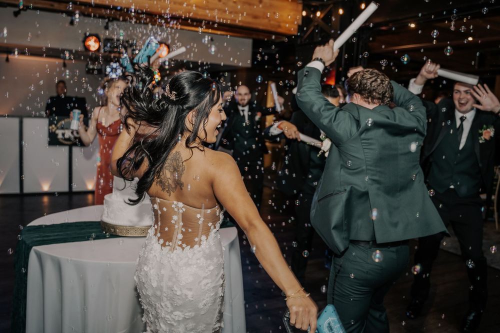 Wedding reception guests dancing and celebrating while confetti falls at an indoor venue during a lively party.
