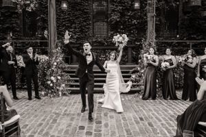 A black and white wedding celebration on brick steps with wedding party members and floral arrangements at an ivy-covered venue.