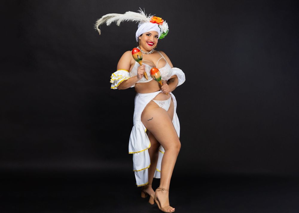 Retro-inspired photoshoot with white costume and feather accessories against dark background.