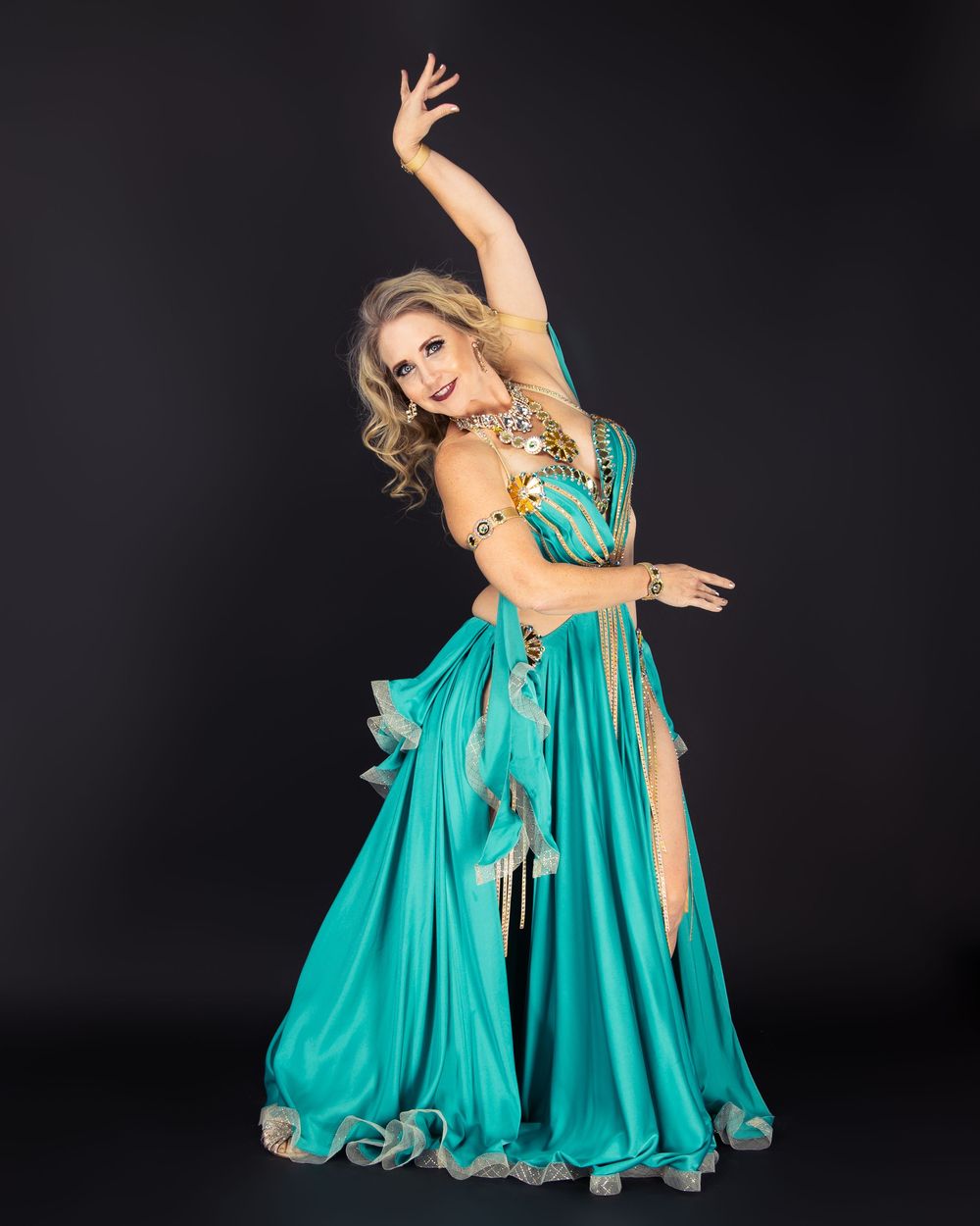 Dynamic poses in flowing turquoise evening gown against black background.