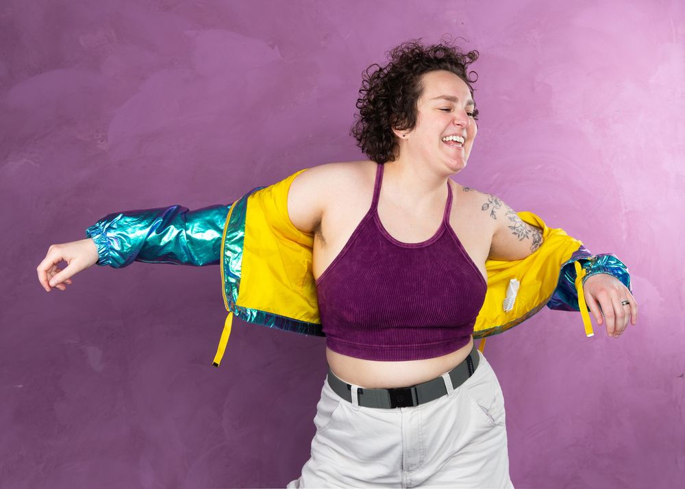 Fashion model in purple top and white pants strikes dynamic poses against pink backdrop.