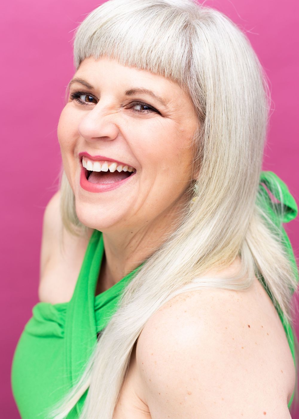 Bright fashion portraits in vibrant green sweater against pink background.