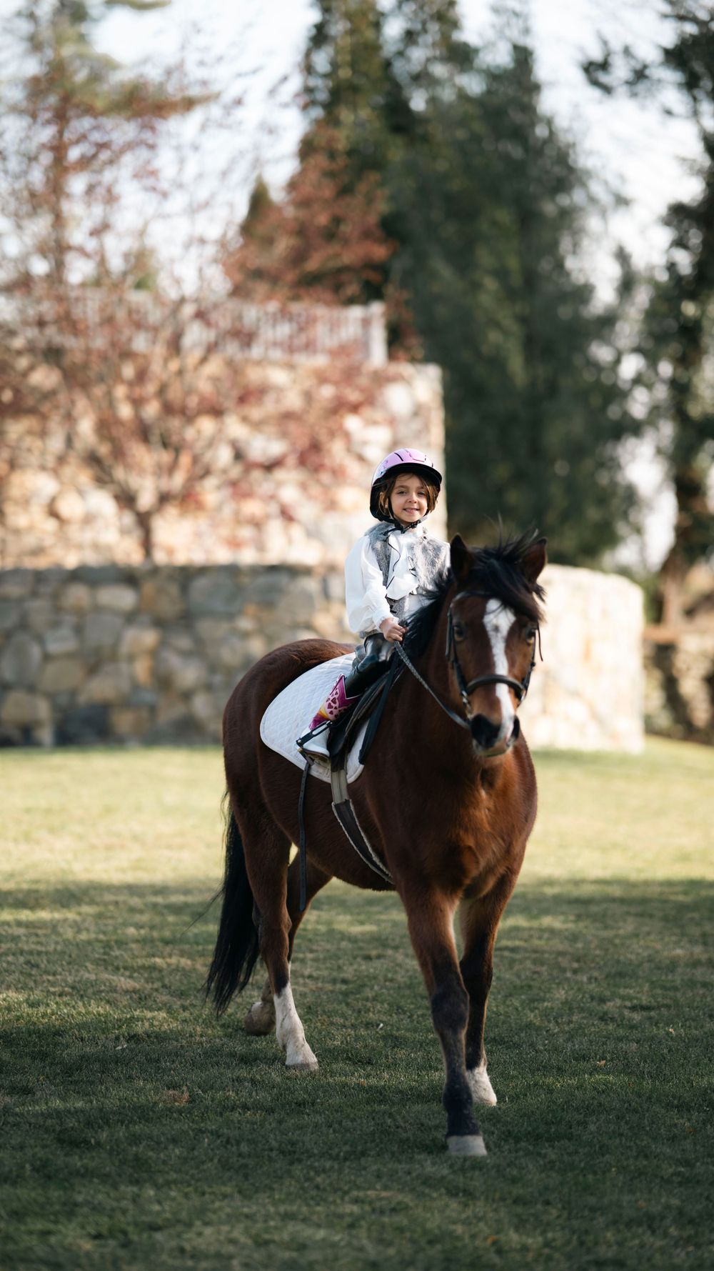 Rider in white outfit on brown and white horse in scenic countryside setting.