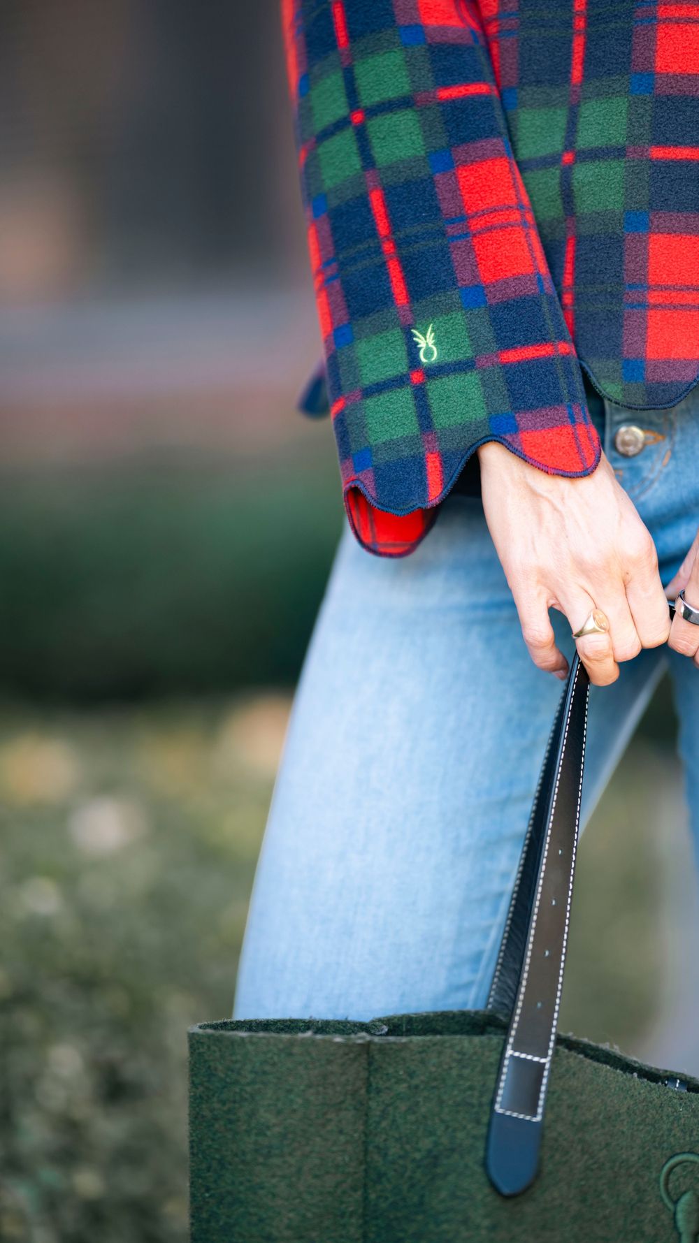 Close-up of plaid fleece sleeve, rings, and green tote bag handle.