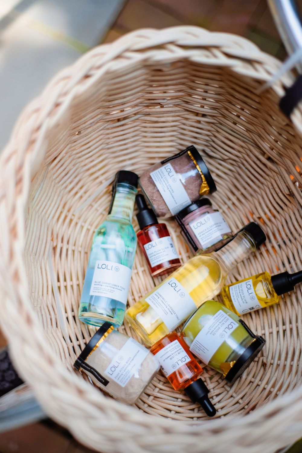 Various labeled bottles and products arranged in a woven basket.