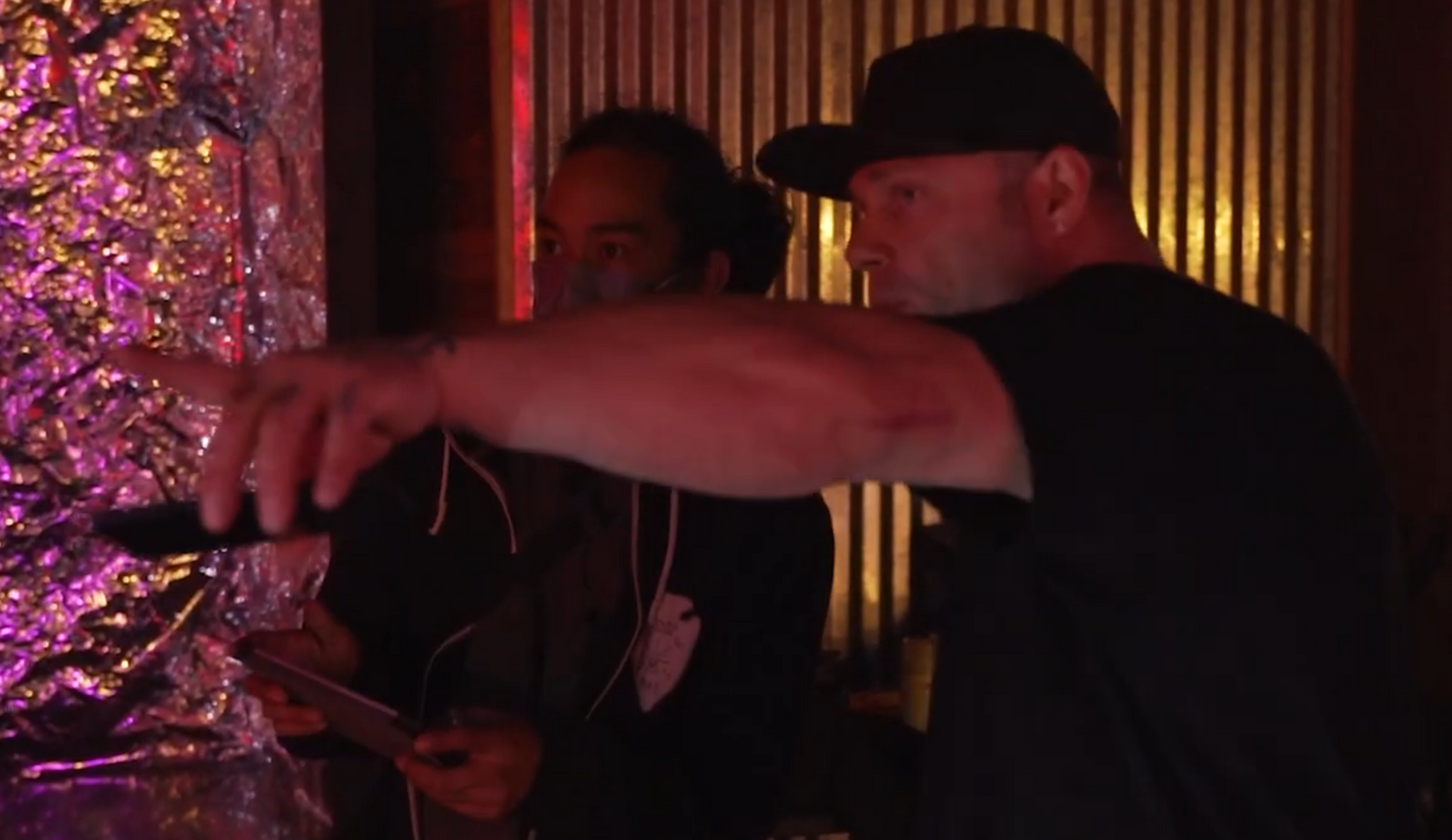 Two DJs mixing music at a darkly lit venue with purple lighting effects.