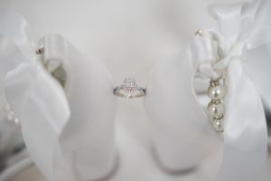 Elegant diamond engagement ring displayed between white ribbons in soft lighting.