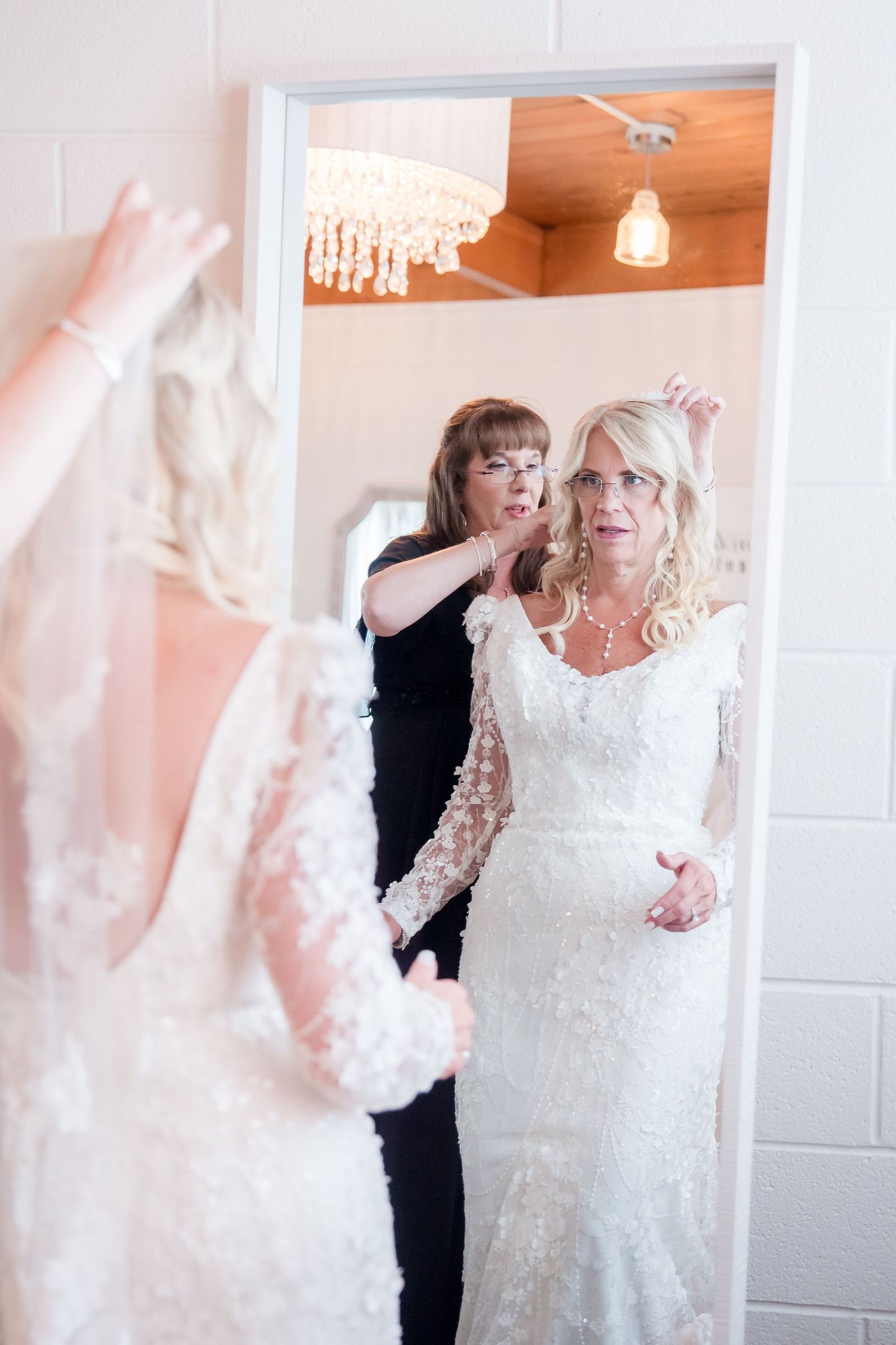 A couple dancing and twirling in a white room, with the bride wearing a flowing white lace wedding dress.