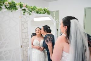 Wedding preparation scene with bride and family members in white decorated room.