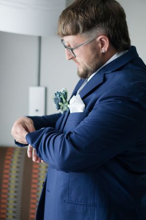 A person in a navy blue suit jacket sniffs their sleeve in a sequence of progressive close-up shots.