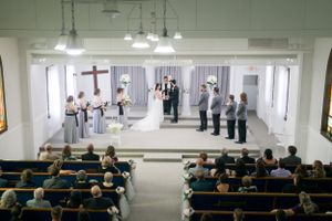Church wedding ceremony from back of sanctuary showing guests seated in wooden pews.