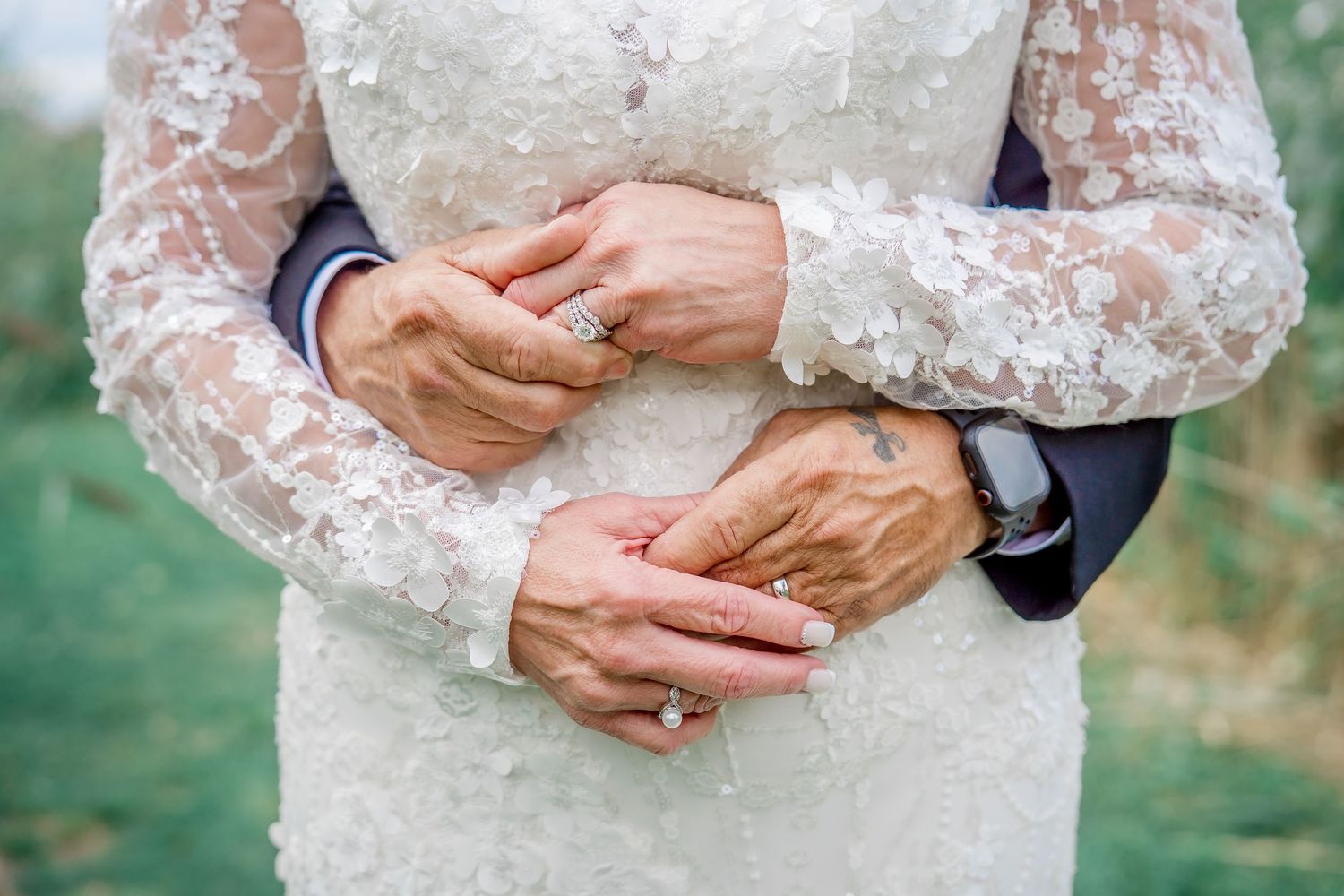 Close-up shots of hands with wedding rings and lace sleeves in a romantic outdoor setting.
