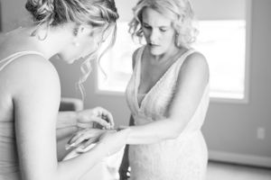 An intimate black and white moment of wedding dress preparation before the ceremony.
