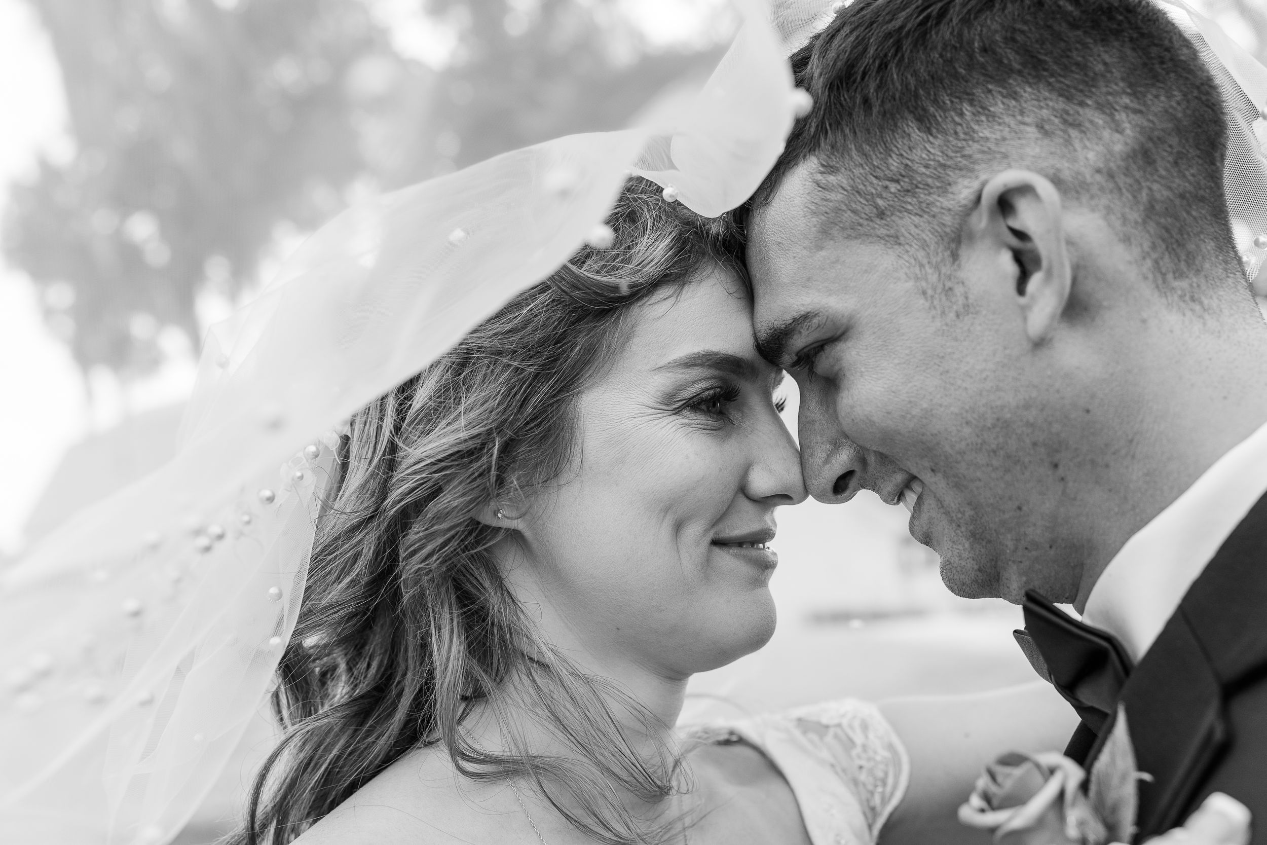 Black and white close-up of a bride and groom sharing an intimate moment with their foreheads touching.
