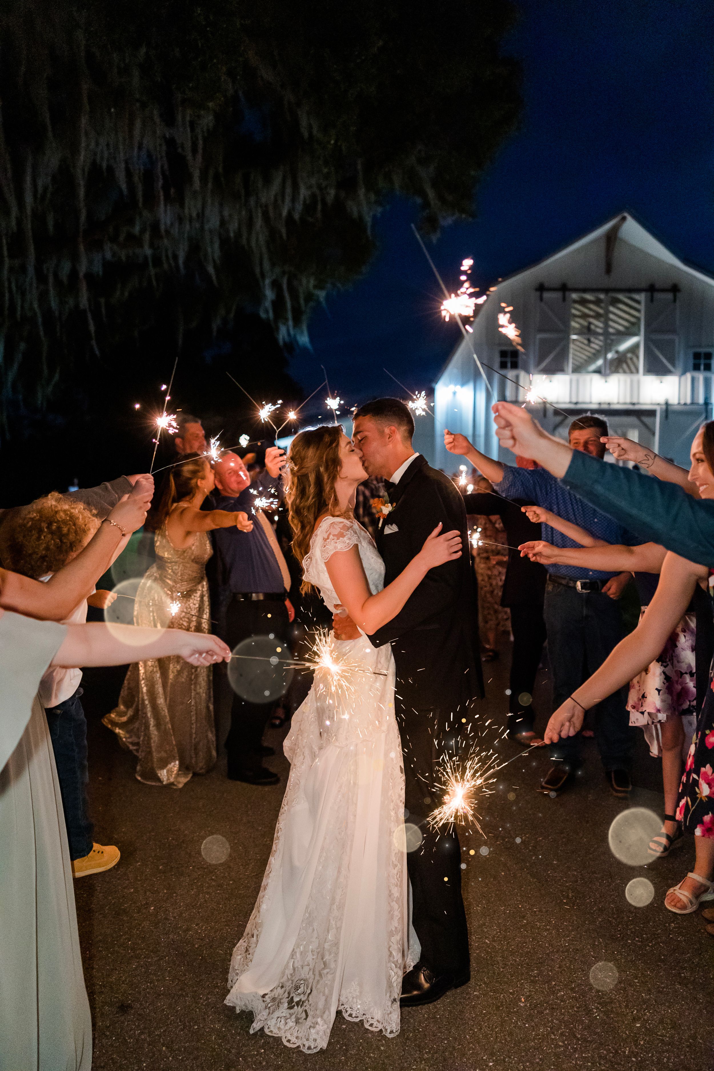 Wedding guests celebrate with sparklers at night during a romantic outdoor reception celebration.