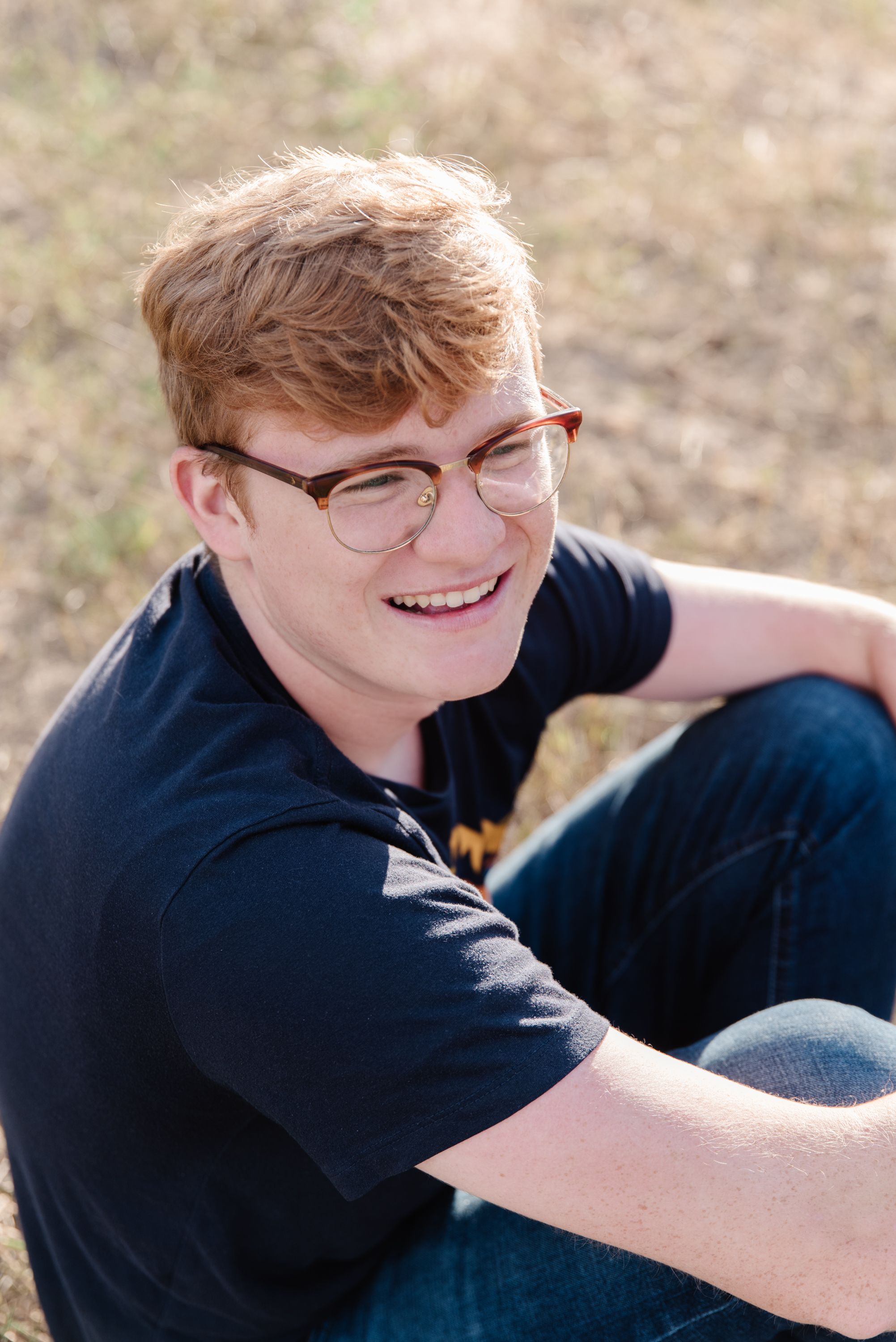 Person in navy shirt sitting outdoors with natural background.