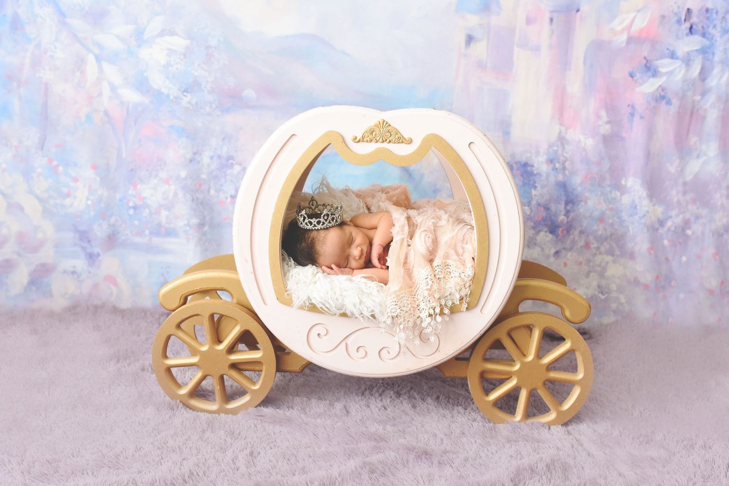 A decorative white and gold carriage ornament with a sleeping baby figure inside displayed against a soft blue backdrop.