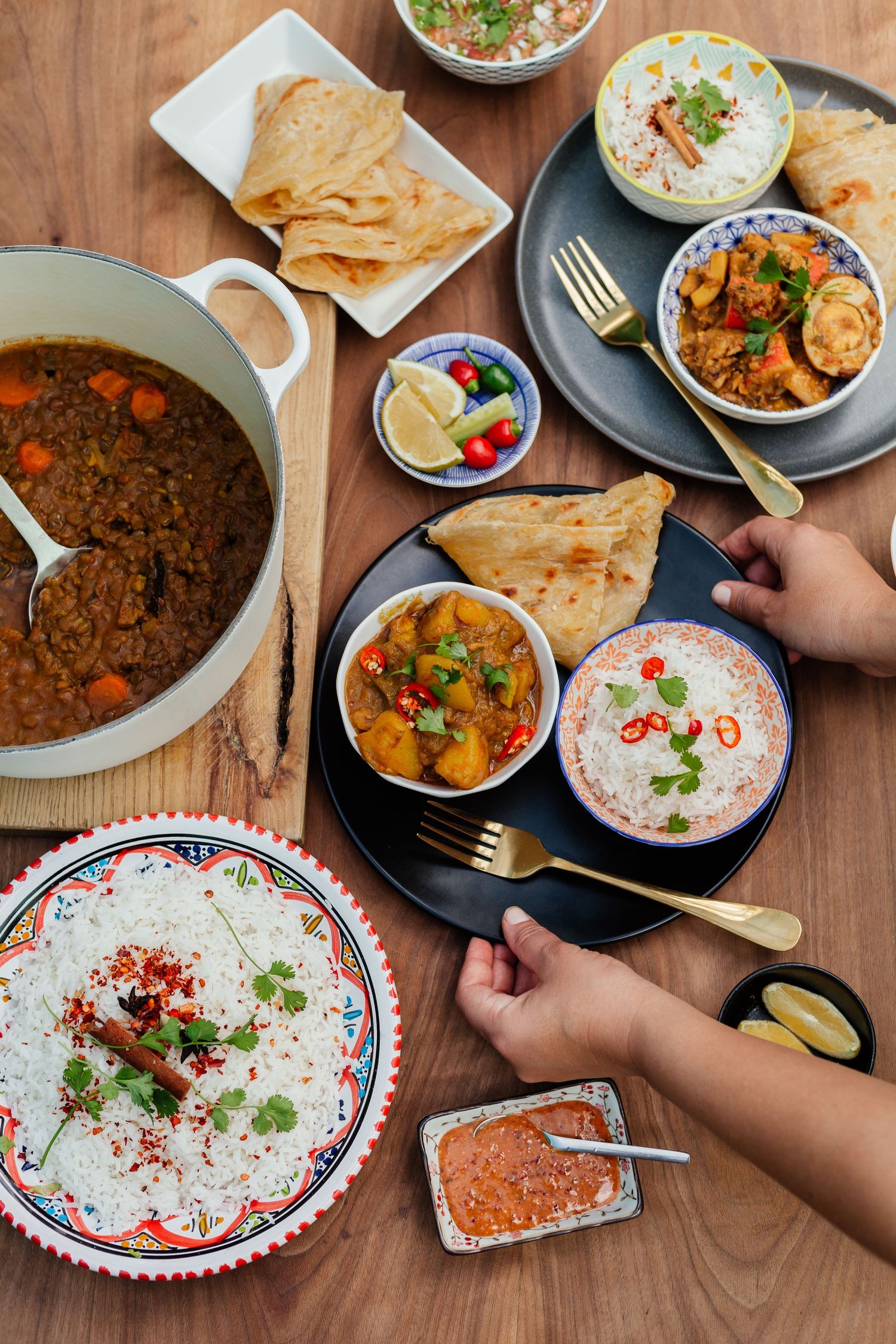 Overhead view of Mexican food spread with tacos, rice, and garnishes on wooden table.