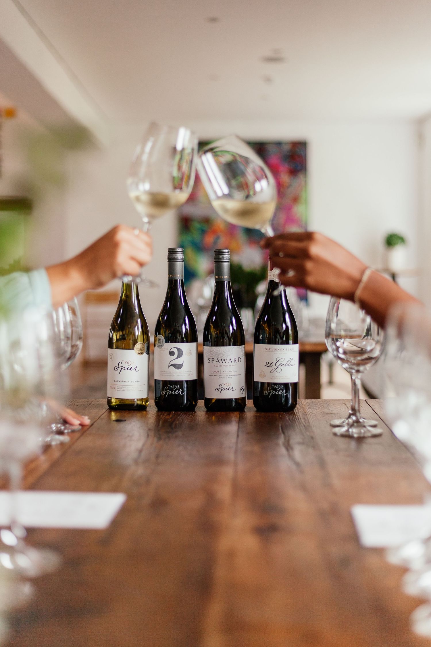 Wine tasting setup with multiple bottles and glasses arranged on a rustic wooden table.