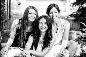 A black and white outdoor portrait of three people sitting together and smiling at the camera.