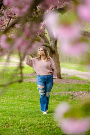 A spring portrait in a blooming cherry blossom garden showing soft pink flowers framing a casual outdoor scene.