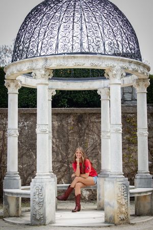 Ornate white stone gazebo with decorative domed roof and classical columns in a garden setting.