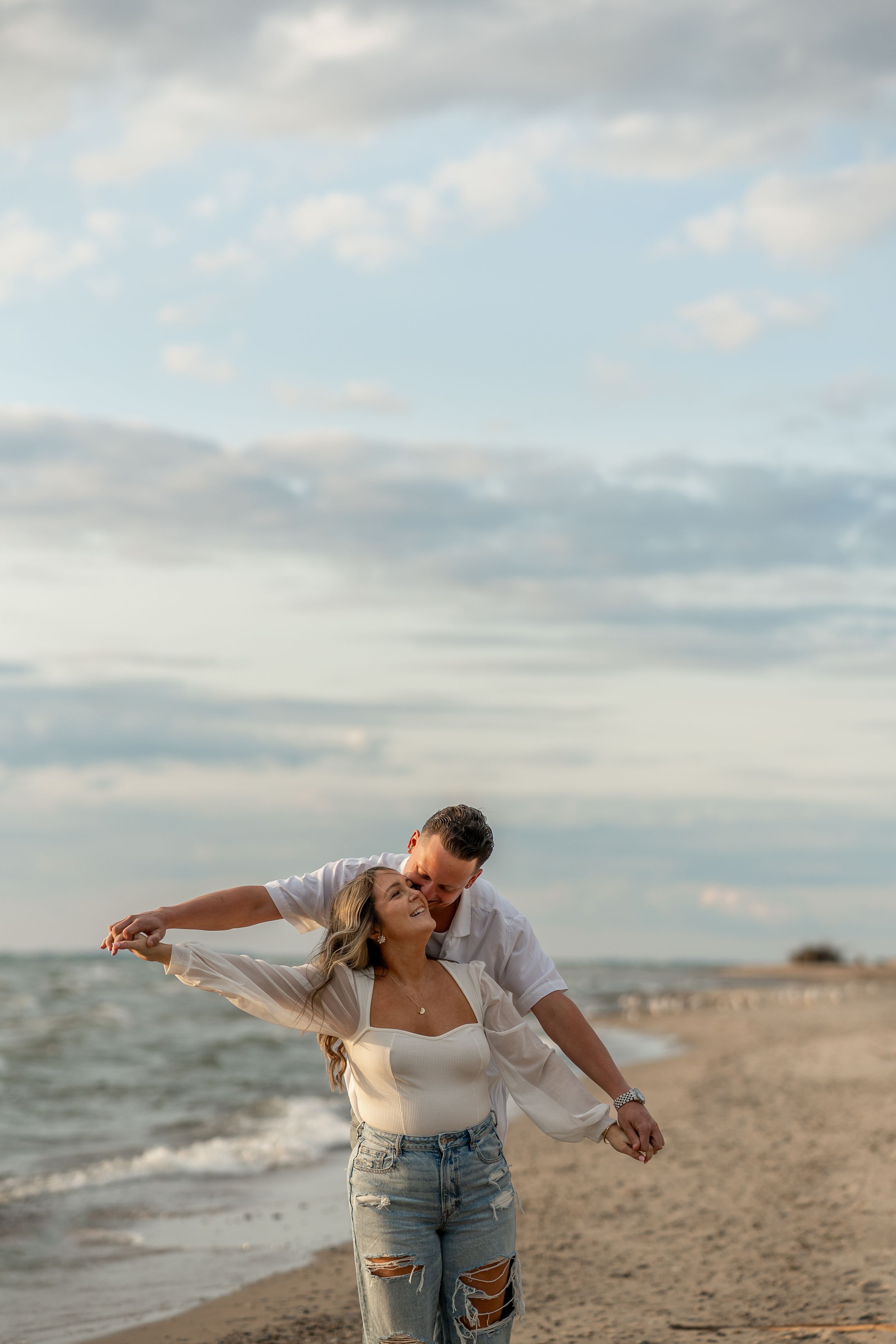 Playful moment between couple on beach shoreline during golden hour.