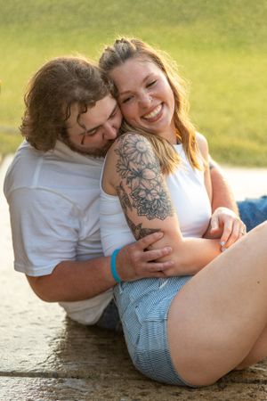 Couple shares intimate moment on concrete surface during outdoor photoshoot.