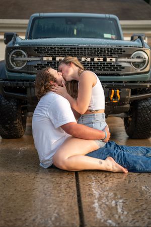 Romantic couple poses in front of vintage Ford Bronco during sunset photoshoot.