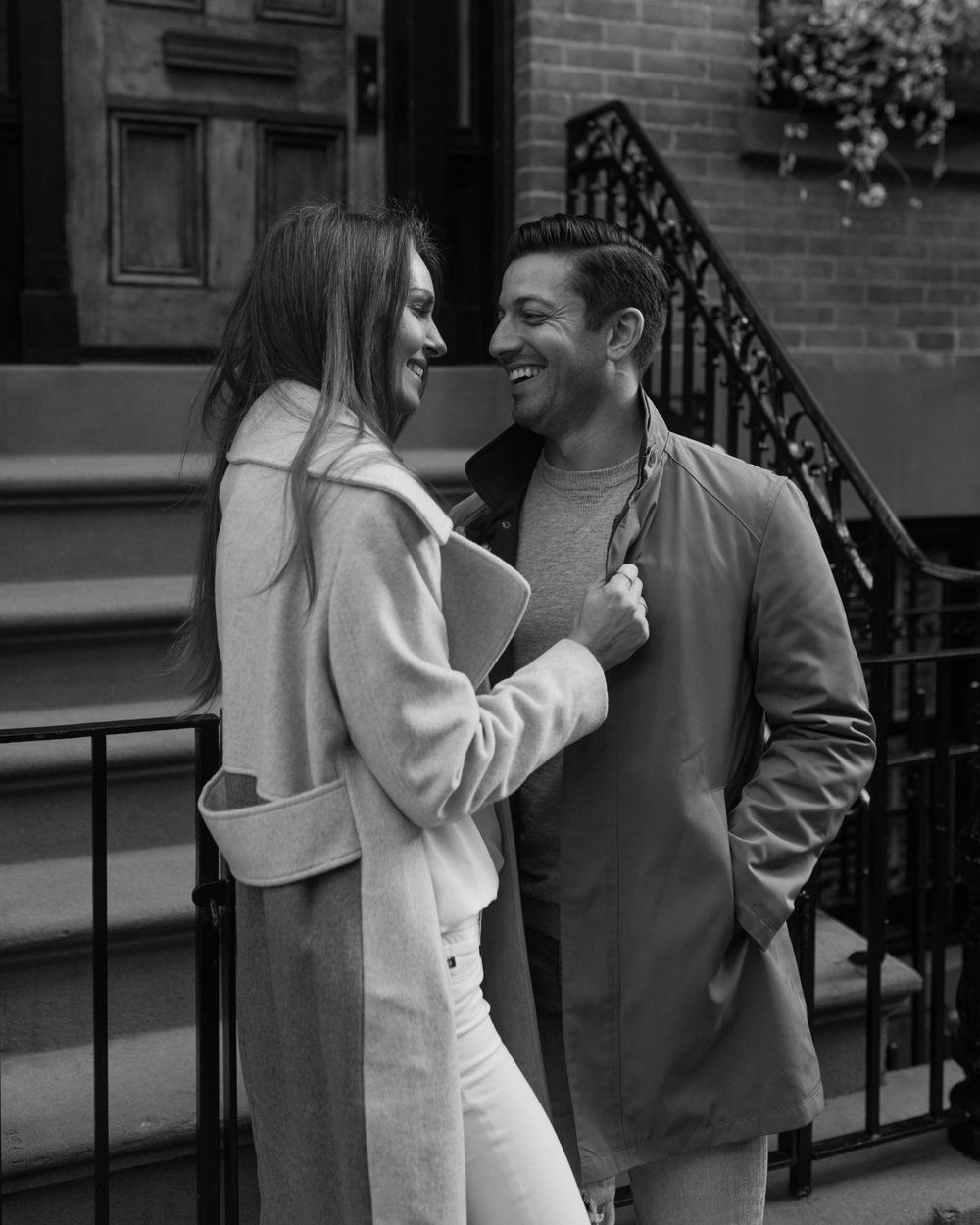 A black and white image of a couple sharing an intimate moment on brownstone steps.