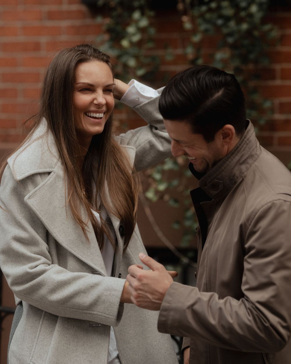 Candid moment of a couple laughing together while wearing matching winter coats.
