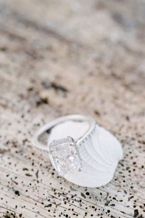 A sparkling diamond engagement ring resting on a textured white surface.