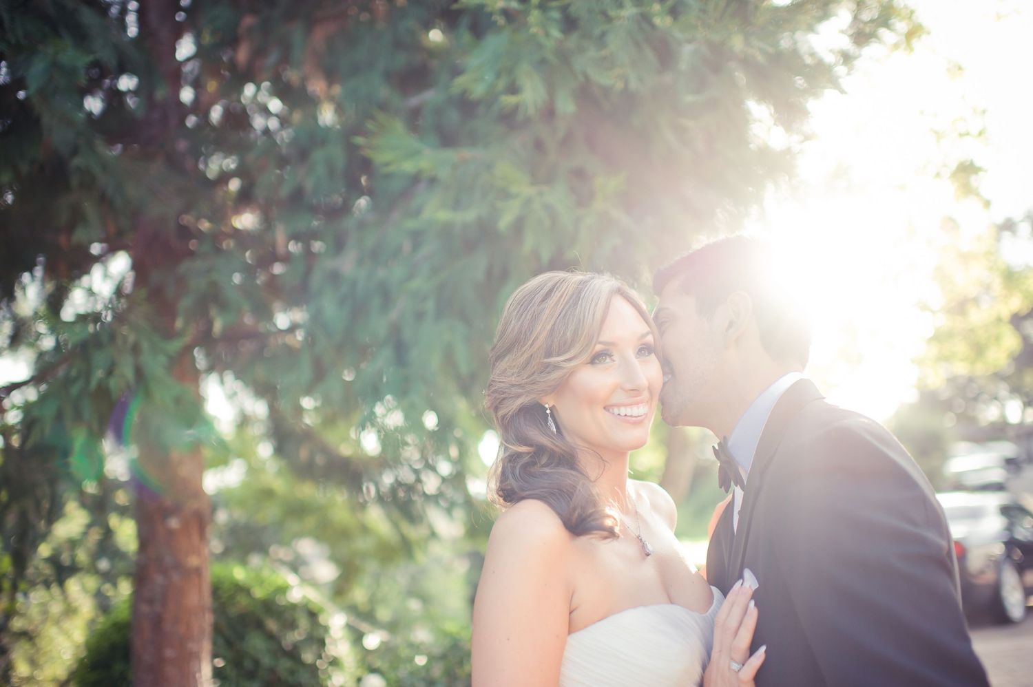 A romantic couple walks hand in hand down a scenic dirt path in golden sunlight while wearing formal wedding attire.