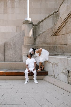 Series of photos showing two dancers in white outfits performing coordinated floor movements against a stone wall.