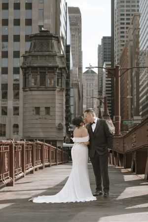 Bride and groom sharing a romantic kiss on a historic Chicago bridge with stunning downtown skyscrapers in the background.