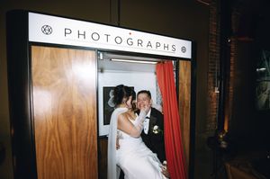 Bride and groom sharing a kiss inside a vintage photo booth at their wedding.