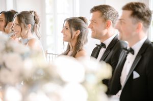 Elegant wedding guests in formal attire laughing and smiling during a reception ceremony.