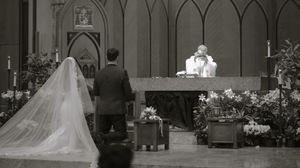 Black and white photo of a bride and groom standing at the altar during a church wedding ceremony.