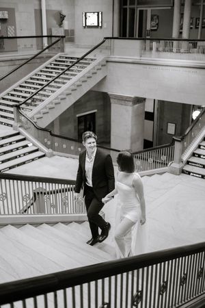 Black and white photo sequence of a couple descending an elegant marble staircase in formal wedding attire.
