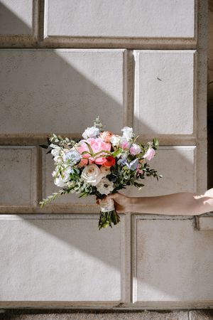 Pink and white floral arrangement decorates a modern architectural wall feature with geometric cutouts and shadows.