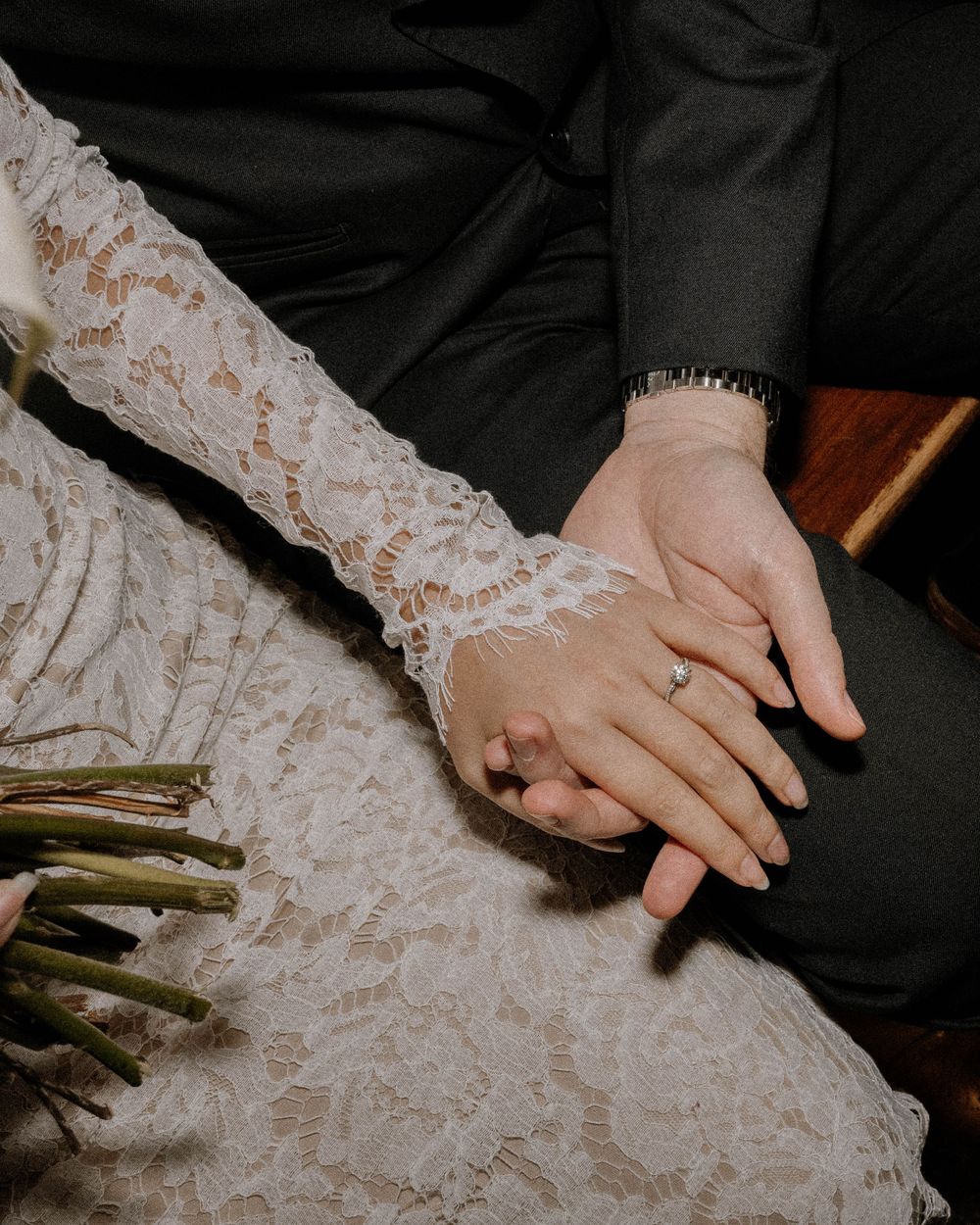 A close-up of hands embracing, with delicate white lace dress fabric and wedding bouquet details visible. Best wedding photographers Chicago