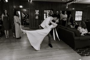 A couple dances in a dramatic dip pose during a romantic moment on a wooden dance floor.