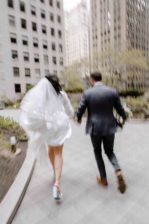 Chicago wedding photographer capturing candid moments of a bride and groom running joyfully through the city streets
