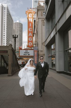 Bride and groom walking hand-in-hand past the iconic Chicago Theatre marquee sign.