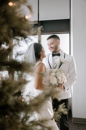 Wedding couple shares intimate moments in a modern indoor setting with natural light filtering through windows.