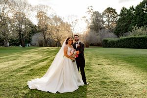 A couple shares romantic moments in a sunlit garden setting during their elegant outdoor wedding celebration.